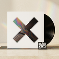 BVRS con portada de X iridiscente y vinilo negro en un entorno cálido
