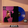 Escena editorial BVRS cálida de Slayyyter con portada y vinilo azul protagonistas entre reflejos rosa y ámbar