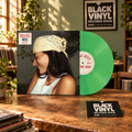 Vinilo verde y portada en una escena editorial BVRS sobre un mostrador de madera.
