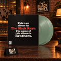 Portada negra de Brothers de The Black Keys y vinilo verde grisáceo en un estudio nocturno