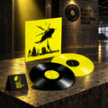 Funda amarilla con helicóptero y dos vinilos, uno negro y otro amarillo, en escena BVRS